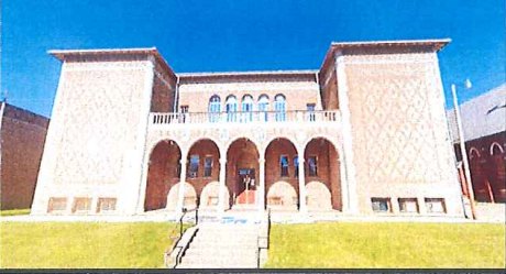 The former St. Agnes school, a symmetrical pale-brick building with an arcaded entrance / La antigua escuela de St. Agnes, un edificio simétrico de ladrillo claro con entrada porticada