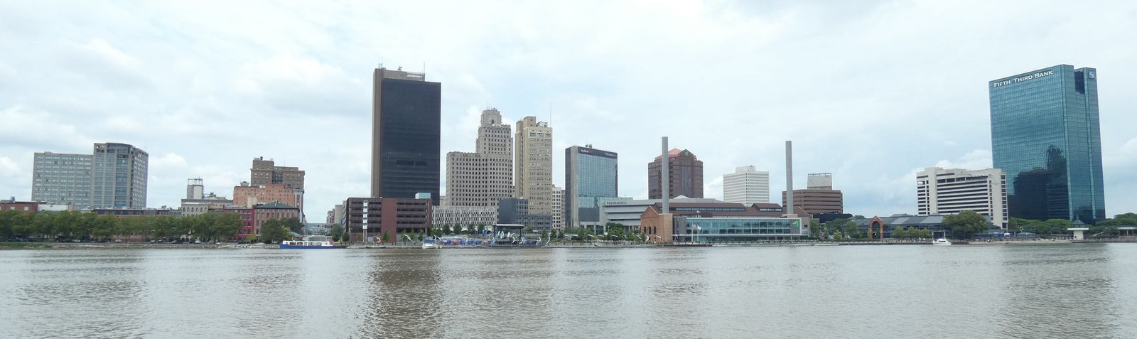 The downtown Toledo skyline seen from across the Maumee River under an overcast summer sky / El horizonte del centro de Toledo visto desde el otro lado del río Maumee bajo un cielo nublado de verano
