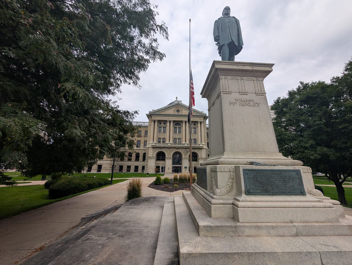 The bronze statue of President William McKinley on the lawn of the Lucas County Courthouse in Toledo, with the pedestal plaques in frame. / La estatua de bronce del presidente William McKinley en el jard&iacute;n del Palacio de Justicia del condado de Lucas, en Toledo, con las placas del pedestal a la vista.